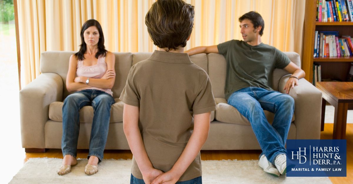 A child stands between a stern-looking woman and a man on a sofa, depicting family tension. The image includes a logo for HARRIS HUNT & DEEN, PA. MARITAL & FAMILY LAW.